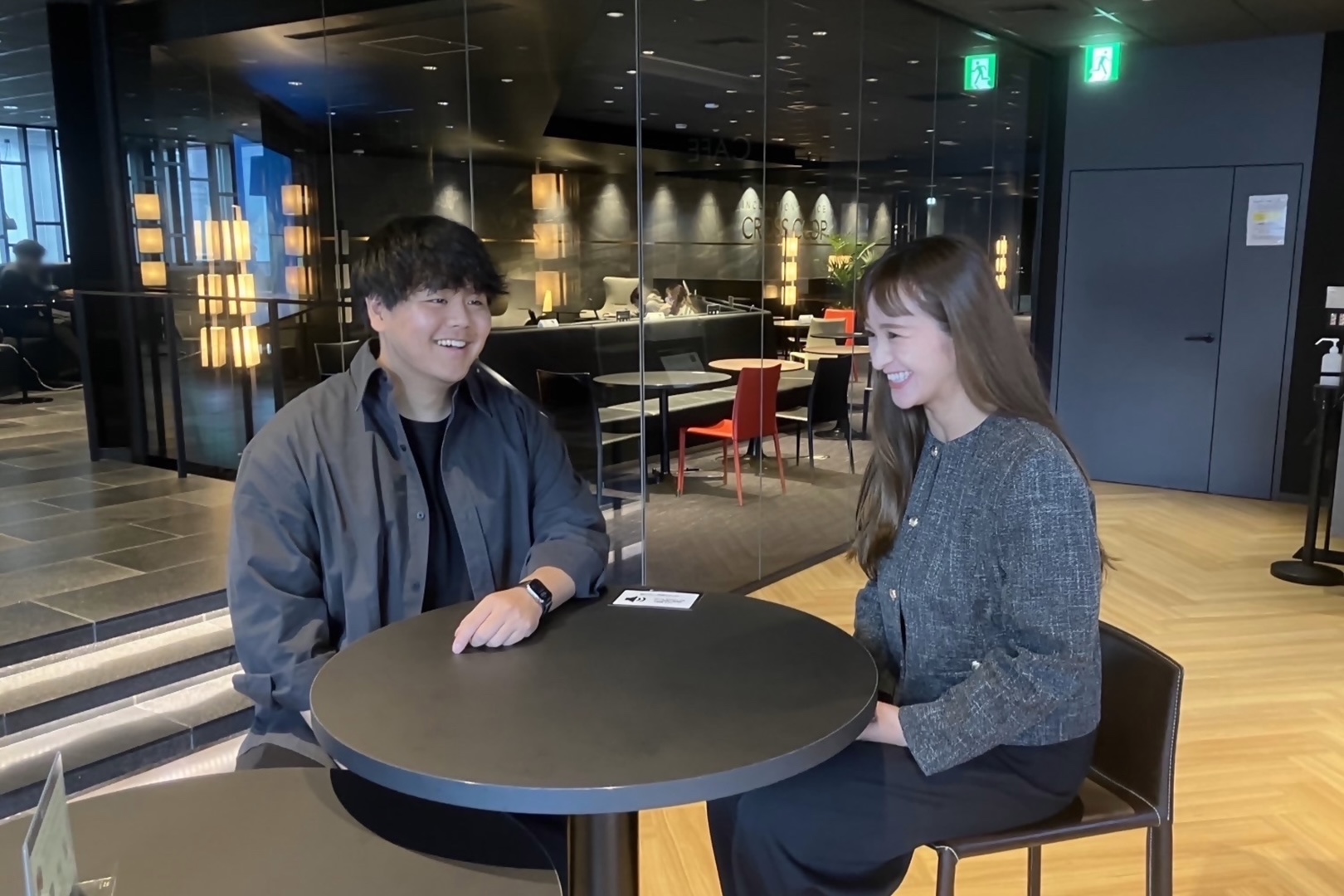 柔らかな照明に包まれたオープンスペースでのコミュニケーション。穏やかな雰囲気の中で、前向きな会話が交わされています。